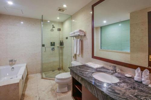 a bathroom with a sink and a toilet and a shower at Jincheng Pacific Hotel in Jincheng