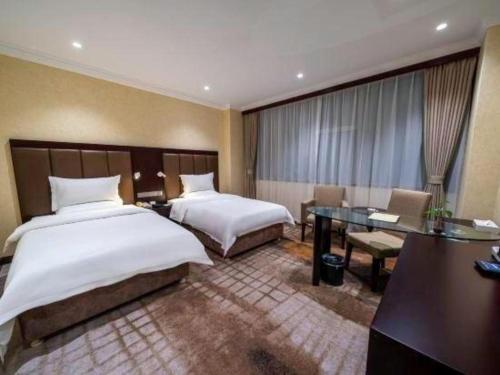 a hotel room with two beds and a desk at Jincheng Pacific Hotel in Jincheng
