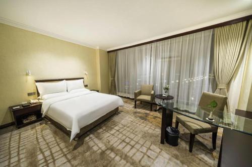 a hotel room with a bed and a glass table at Jincheng Pacific Hotel in Jincheng