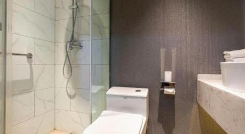 a bathroom with a shower and a toilet and a sink at Magnotel Business Jining Huancheng North Road in Jining
