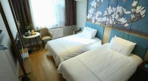 a hotel room with two beds and a chair at Magnotel Business Jining Huancheng North Road in Jining