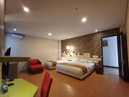 a bedroom with two beds and a brick wall at Griya Jogja Hotel in Yogyakarta