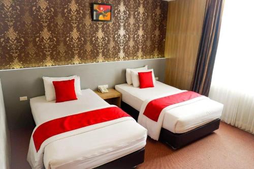 two beds in a hotel room with red pillows at Hotel Mekkah Banda Aceh in Banda Aceh