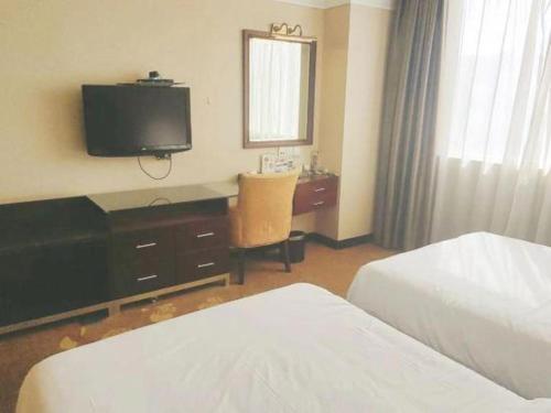 a hotel room with two beds and a desk with a television at Fuzhou Fuqing Ruixin Hotel in Fuzhou
