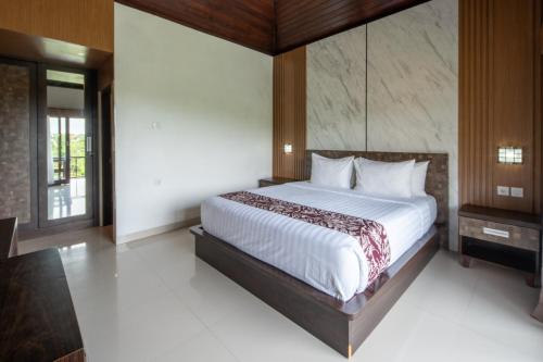 a bedroom with a large bed with white sheets at Abasan Hill Hotel and Spa in Nusa Penida