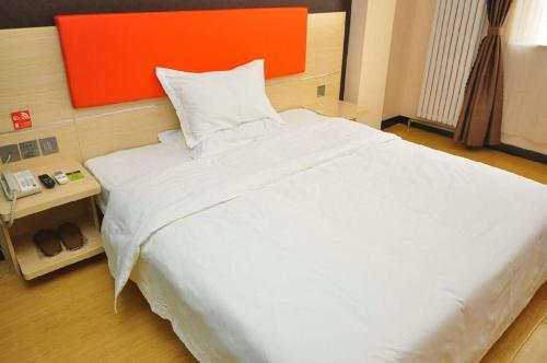 a large white bed in a bedroom with an orange headboard at 7 Days Premium Dezhou Qingyun Nanhuan Building Materials Market in Dezhou