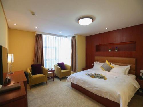 ein Hotelzimmer mit einem Bett und zwei Stühlen in der Unterkunft Qingdao TianRun JinWang Hotel in Qingdao