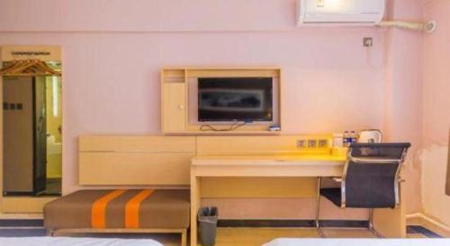 a room with a desk and a tv on a wall at 7 Days Premium Hohhot Hailiang Square in Hohhot