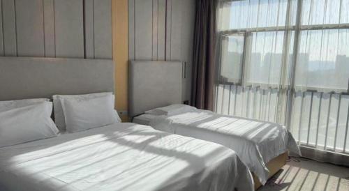 two beds in a hotel room with a window at Lavande Hotel Yichang Railway East Station Branch in Yichang