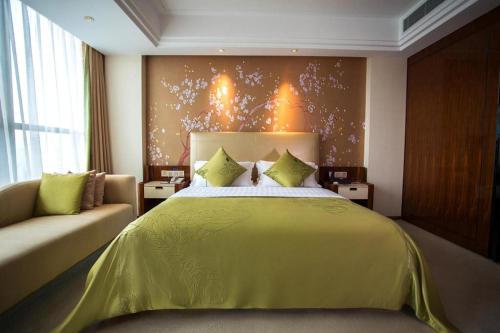 a bedroom with a large bed with a yellow bedspread at Yongzhou Chuang Fa Cheng XiaoXiangYi Hotel in Guzhuting