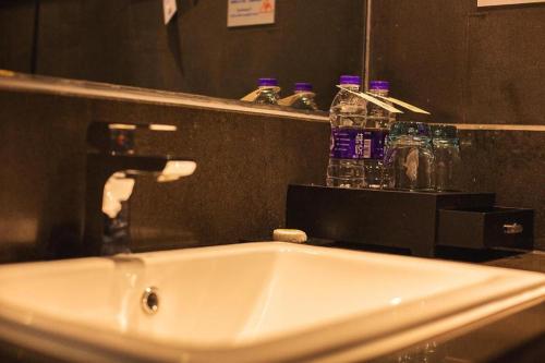 a bathroom sink with a faucet in front of a mirror at Yongzhou Chuang Fa Cheng XiaoXiangYi Hotel in Guzhuting