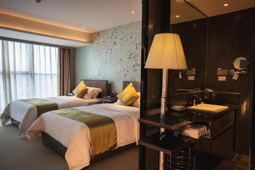 a hotel room with two beds and a lamp at Yongzhou Chuang Fa Cheng XiaoXiangYi Hotel in Guzhuting