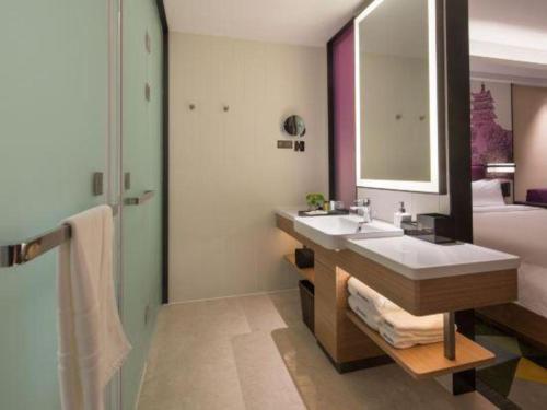 a bathroom with a sink and a bed and a mirror at Hampton by Hilton Suzhou XiangCheng in Suzhou