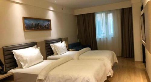 a hotel room with two beds and a window at Metropolo Hotel Qingdao Wusi Square Xiaomaidao in Qingdao