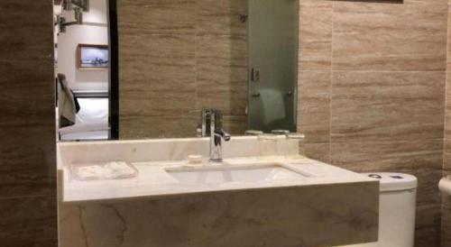 a bathroom with a sink and a mirror and a toilet at Metropolo Hotel Qingdao Wusi Square Xiaomaidao in Qingdao