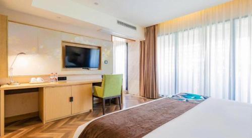 a hotel room with a bed and a desk and a television at James Joyce Coffetel Chengdu Jichang Road Shenxianshu in Chengdu