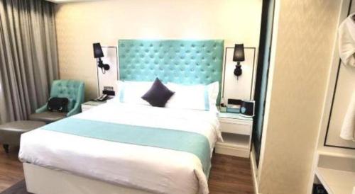 a bedroom with a large bed with a blue headboard at Xana Lite Korla Shihua Avenue Longquehe in Korla