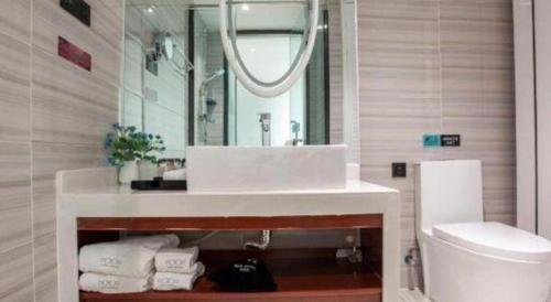 a bathroom with a sink and a mirror and a toilet at Xana Lite Korla Shihua Avenue Longquehe in Korla