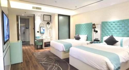 a hotel room with two beds and a television at Xana Lite Korla Shihua Avenue Longquehe in Korla