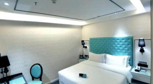 a bedroom with a white bed and a blue headboard at Xana Lite Korla Shihua Avenue Longquehe in Korla