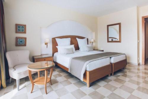a bedroom with a bed and a chair and a table at Iberostar Selection Kantaoui Bay in Port El Kantaoui