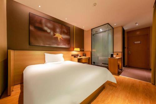 a bedroom with a large white bed and a bathroom at IU Hotel Kunming Jinma Bijifang Joy City in Kunming