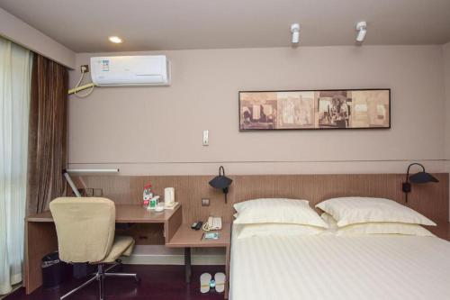 a hotel room with a bed and a desk with a computer at Jinjiang Inn Style Shijiazhuang Zhongshan Xi Road Yuxi Park in Shijiazhuang