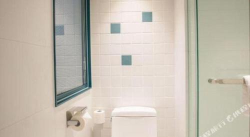 a bathroom with a toilet and a glass shower door at Magnotel Harbin Songbei Wanda Wenlvcheng in Harbin