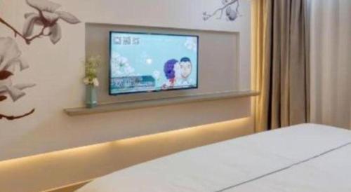 a bedroom with a flat screen tv on a wall at Magnotel Harbin Songbei Wanda Wenlvcheng in Harbin