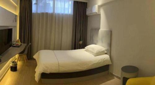 a hotel room with a bed and a television at Magnotel Harbin Songbei Wanda Wenlvcheng in Harbin