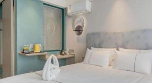 a bedroom with a white bed and a blue wall at Magnotel Harbin Songbei Wanda Wenlvcheng in Harbin