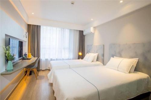 a hotel room with two beds and a desk at Magnotel Harbin Songbei Wanda Wenlvcheng in Harbin