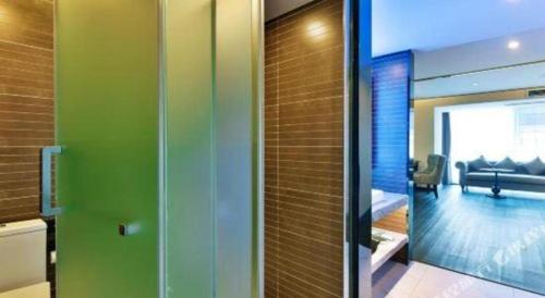 a bathroom with green walls and a glass door at Xana Hotelle Chengdou Xindu Sanhechang Metro Station in Chengdu
