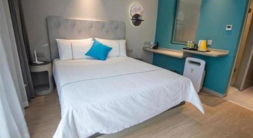 a bedroom with a large white bed with blue walls at Magnotel Hotel Suzhou Guanqian Street Pingjiang Road in Suzhou