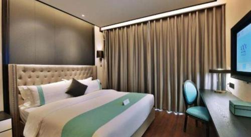 a bedroom with a large bed and a television at Xana Hotelle Chengdou Xindu Sanhechang Metro Station in Chengdu