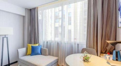 a living room with a couch and a table and a window at Echarm Hotel Zibo Gaoqing Zhongcheng Inernational in Zibo