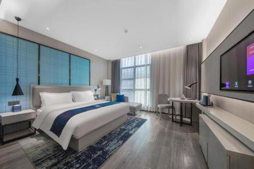 a bedroom with a bed and a flat screen tv at Echarm Hotel Huaihua Vocational College in Huaihua
