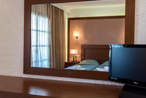 a hotel room with a mirror and a bed at Gaia Garden in Kos Town