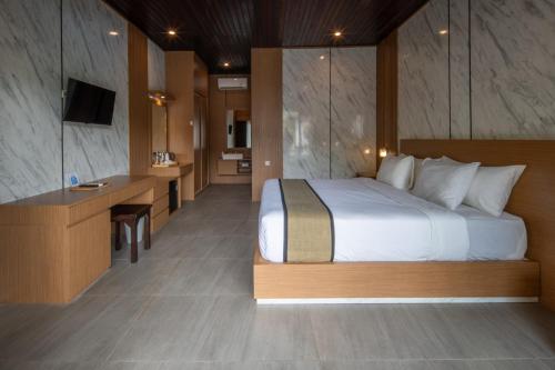 a bedroom with a bed and a desk and a television at Abasan Hill Hotel and Spa in Nusa Penida
