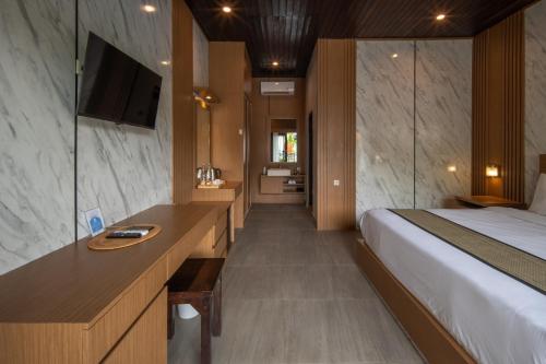 a bedroom with a bed and a desk with a television at Abasan Hill Hotel and Spa in Nusa Penida