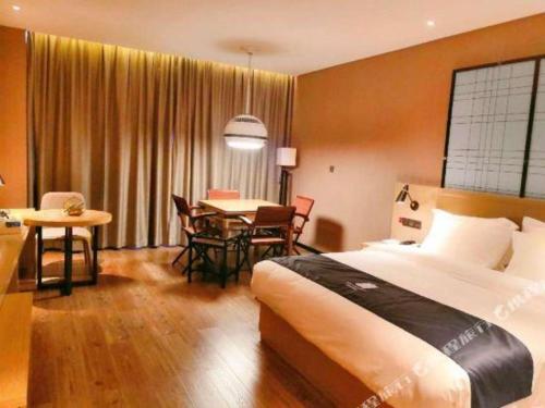 a hotel room with a bed and a table and chairs at Echarm Hotel Changde Taoyuan Walking Street Jinyuan Tower in Changde