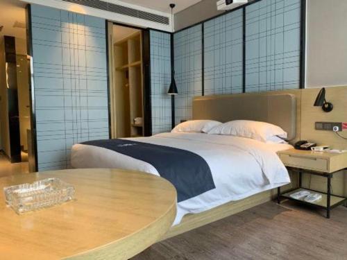 a bedroom with a large bed and a table at Echarm Hotel Changde Taoyuan Walking Street Jinyuan Tower in Changde