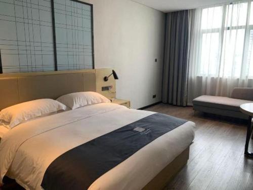 a bedroom with a large bed and a couch at Echarm Hotel Changde Taoyuan Walking Street Jinyuan Tower in Changde
