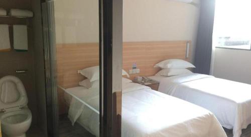 a hotel room with two beds and a toilet at City Comfort Inn Wuhan Guanggu Textile University in Wuhan