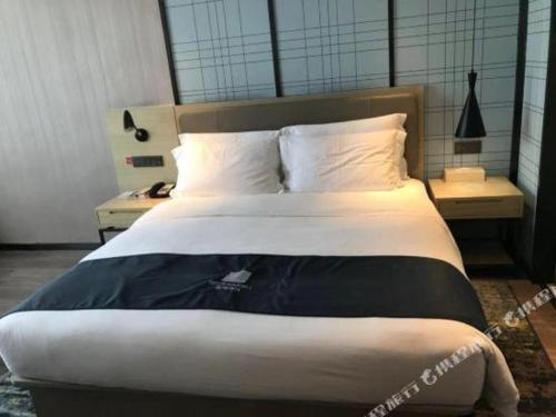 a bedroom with a large bed with a white bedspread at Echarm Hotel Changde Taoyuan Walking Street Jinyuan Tower in Changde