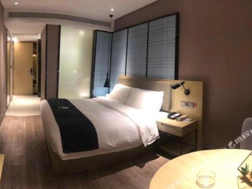 a bedroom with a large bed and a table at Echarm Hotel Changde Taoyuan Walking Street Jinyuan Tower in Changde