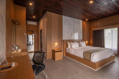 a bedroom with a bed and a desk and a chair at Abasan Hill Hotel and Spa in Nusa Penida