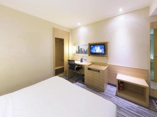 a hotel room with a bed and a desk and a tv at City Comfort Inn Wuhan Zhongnan Road Metro Exit in Wuhan