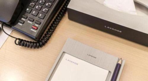 a desk with a cell phone and a telephone at Lavande Hotels Wuhan Guanggu Yangjiawan Metro Station in Wuhan