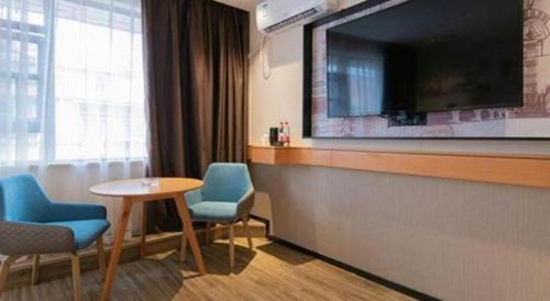 a hotel room with a table and chairs and a large television at City Comfort Inn Kunming High Speed Railway South Station Yongxin Harvard in Kunming